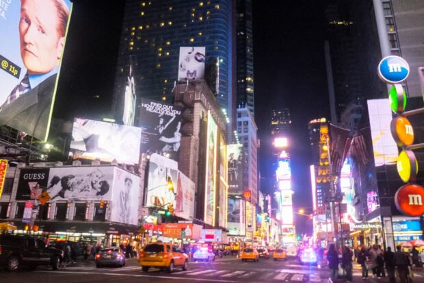 Nighttime cityscape of Broadway with bright lights and busy traffic in New York City