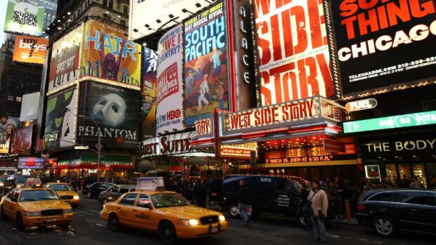 A busy Broadway street scene featuring iconic musical posters including West Side Story and Phantom