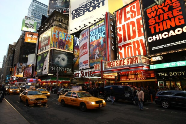Times Square with vibrant Broadway signs and yellow taxis on a busy street at dusk