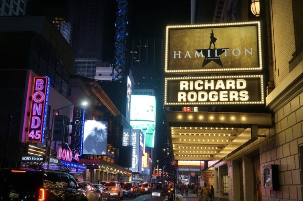 Nighttime Broadway street with Hamilton sign and vibrant theater lights