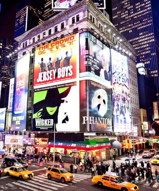 Bright Broadway billboards with Jersey Boys Wicked and Phantom shows in a busy city street scene