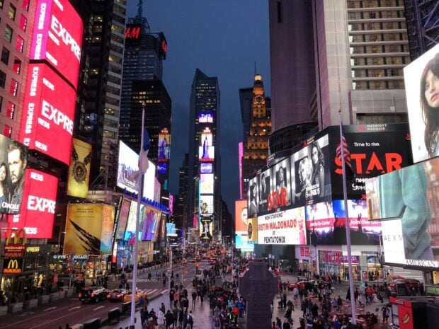 Crowded Broadway street scene at night with bright lights and colorful billboards