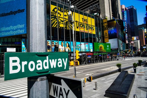 Green Broadway street sign near the Lion King advertisement in Times Square New York