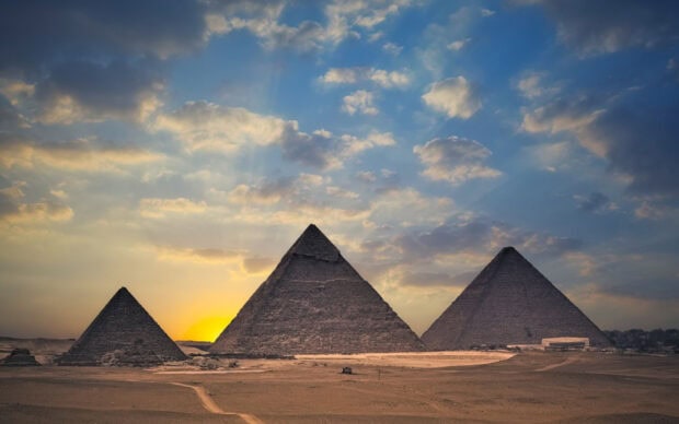 Ancient pyramids in Cairo Egypt under a dramatic sunset sky with scattered clouds