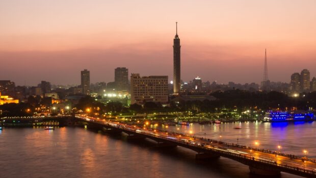 Evening cityscape of Cairo Egypt with illuminated buildings and bridge over the river