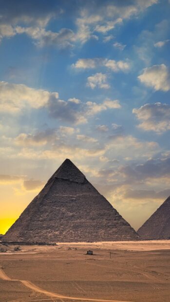 The Great Pyramid in Cairo Egypt stands under a beautiful cloudy sky at sunset