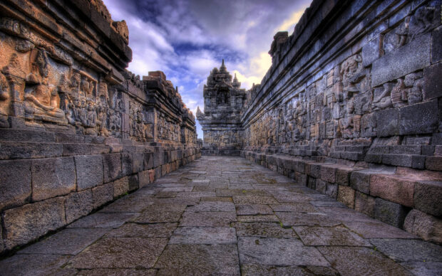Ancient Cambodia temple walls with detailed stone carvings under a cloudy sky