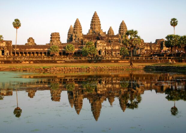 Ancient temple architecture in Cambodia reflected in calm water at sunset