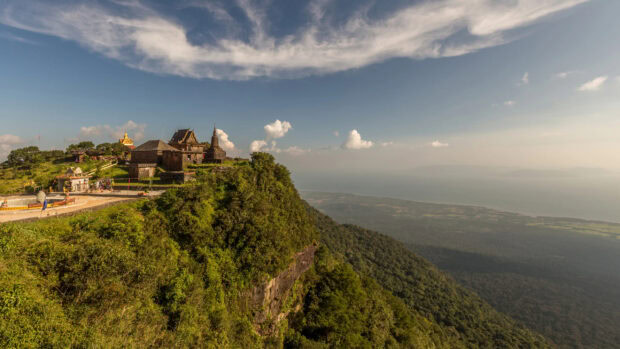 Ancient temple on a hill overlooking green forest and river in Cambodia