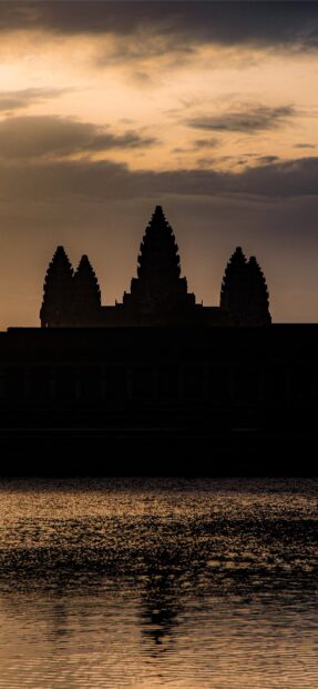The silhouette of Angkor Wat temple reflecting on the water during a beautiful sunset in Cambodia