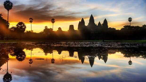 Angkor Wat temple silhouette during sunrise in Cambodia reflecting on water