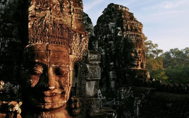 Ancient Cambodia stone faces carved on temple walls in an Angkor archaeological site