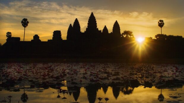 Ancient Cambodia temple silhouette at sunrise reflecting on lotus pond