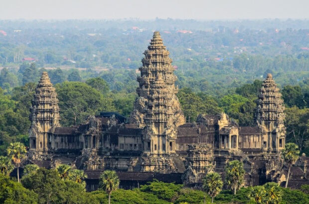 Ancient Cambodia temple surrounded by green forest under clear sky
