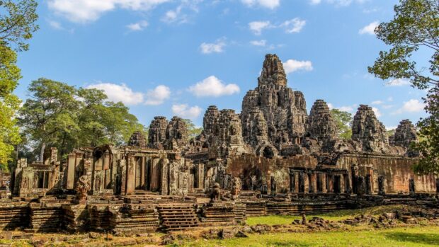 Ancient temple ruins surrounded by trees in Cambodia with clear blue sky
