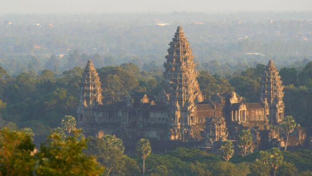 Ancient Khmer temple in Cambodia surrounded by lush green forest at sunrise