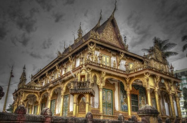 Ornate Cambodian temple architecture with golden decorations under cloudy sky
