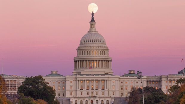 Capitol Hill dome with a full moon above under a pink sky at sunset