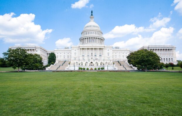 The Capitol Hill building with a bright blue sky and green lawn in front