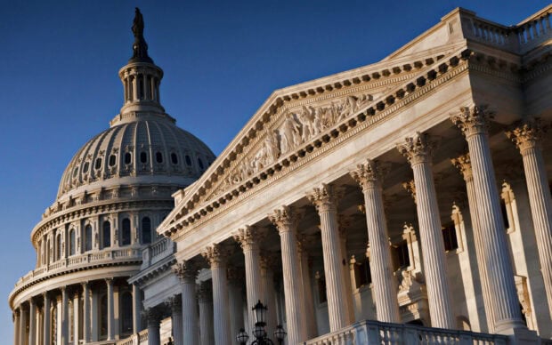 The Capitol Hill building with a detailed dome and classical columns under a clear blue sky