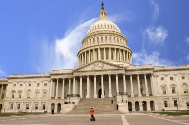 Person riding a Segway in front of Capitol Hill architecture with a clear blue sky