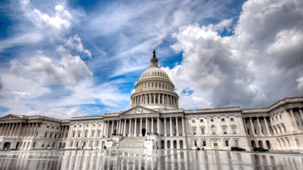 The Capitol Hill building with a dramatic cloudy sky and reflection in a water pool
