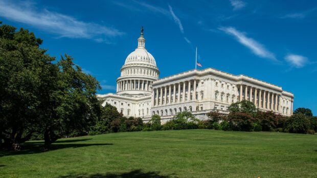 The Capitol Hill building with white dome and green lawn under a clear blue sky