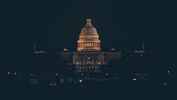 Illuminated Capitol Hill building at night with dark sky and city lights