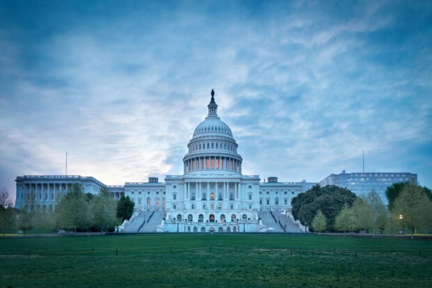 Capitol Hill at sunset with clear sky and green lawn in front of the building