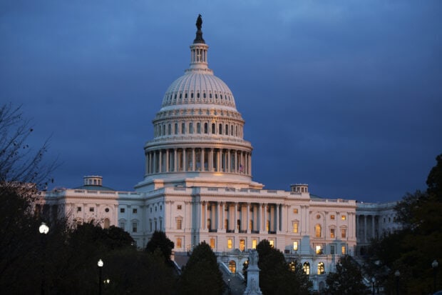 The Capitol Hill building illuminated at dusk with clear sky in the background
