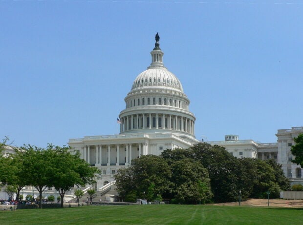 The Capitol Hill dome surrounded by trees and blue sky in a public park