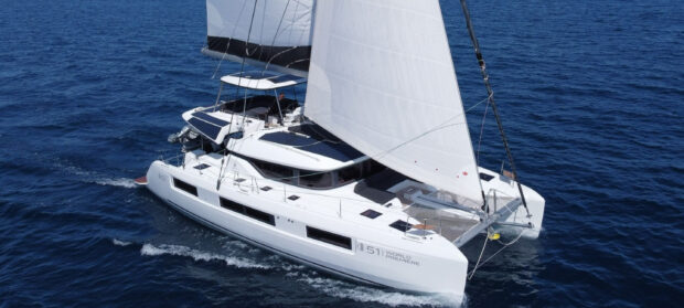 A modern catamaran sailing smoothly on deep blue ocean waters with white sails fully raised
