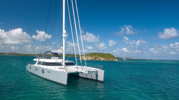 A sleek catamaran sails peacefully on clear turquoise waters with a small island in the background