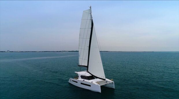 A white catamaran sailing on calm blue ocean waters under a clear sky