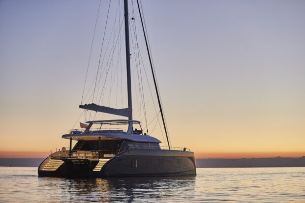 Luxury catamaran resting on calm waters at sunset with clear sky