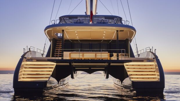 Luxury catamaran with illuminated deck at sunset on calm water