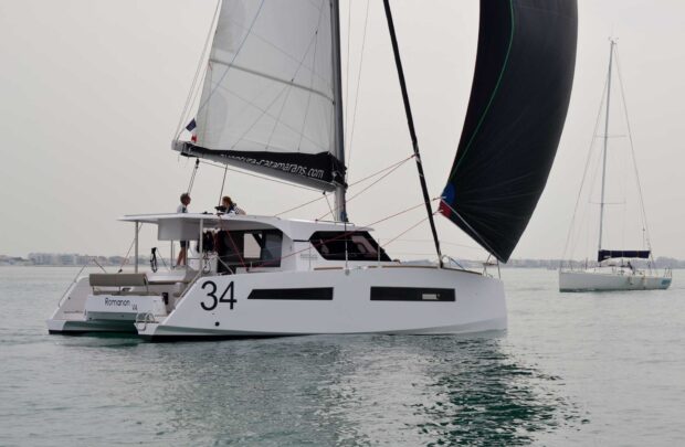 White catamaran sailing with people on board in calm water