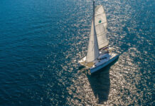 A catamaran sailing on sparkling blue water under bright sunlight