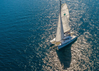 A catamaran sailing on sparkling blue water under bright sunlight