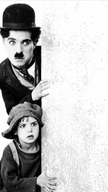 Charlie Chaplin and a child peeking from behind a wall in a classic scene