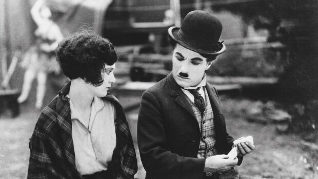 Charlie Chaplin character interacting with a woman in a classic silent film scene