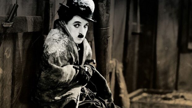 Charlie Chaplin sitting quietly wrapped in a coat in a classic black and white scene