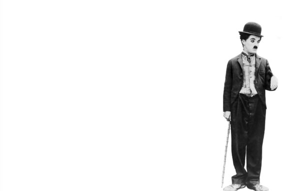 Charlie Chaplin standing with a cane in classic attire in this Charlie Chaplin image
