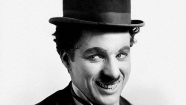 Charlie Chaplin smiling with his classic hat in a black and white portrait