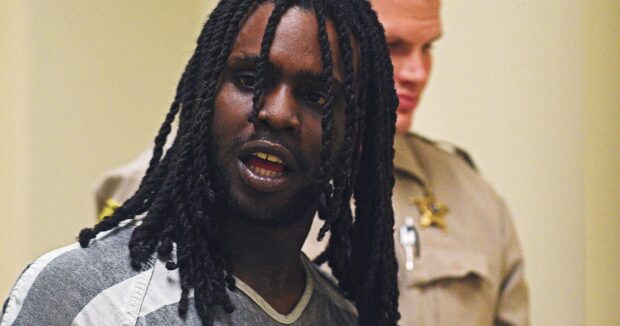 Chief Keef with dreadlocks wearing a striped shirt and talking in a close up shot