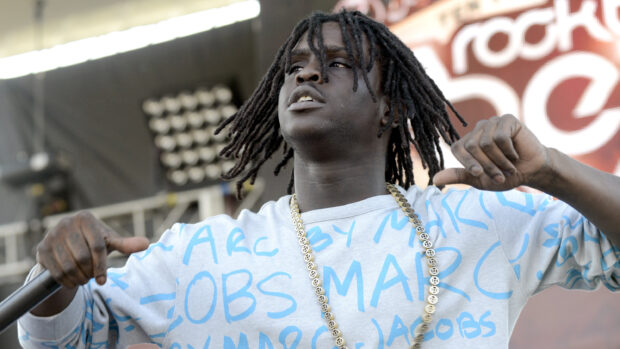 Chief Keef wearing a silver chain performing on stage with a microphone in hand