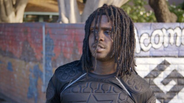 Chief Keef wearing protective gear standing near a graffiti wall
