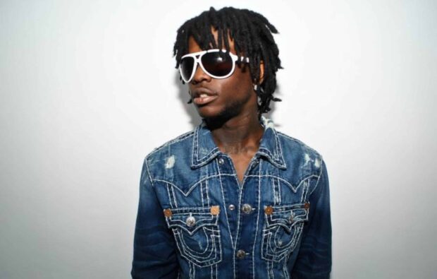 Chief Keef wearing white sunglasses and a denim jacket against a white background