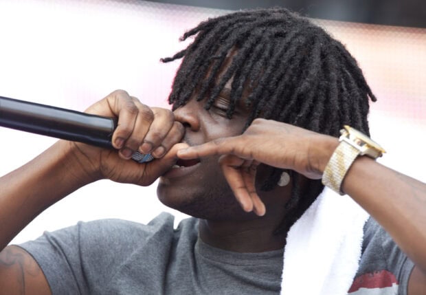 Chief Keef rapping passionately with a microphone during a live performance