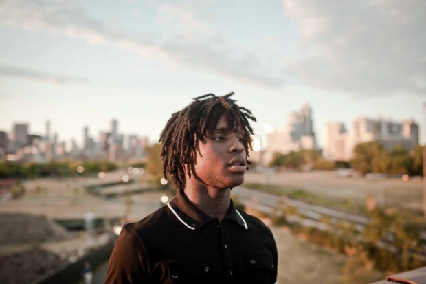 Chief Keef standing outdoors with urban cityscape in the background